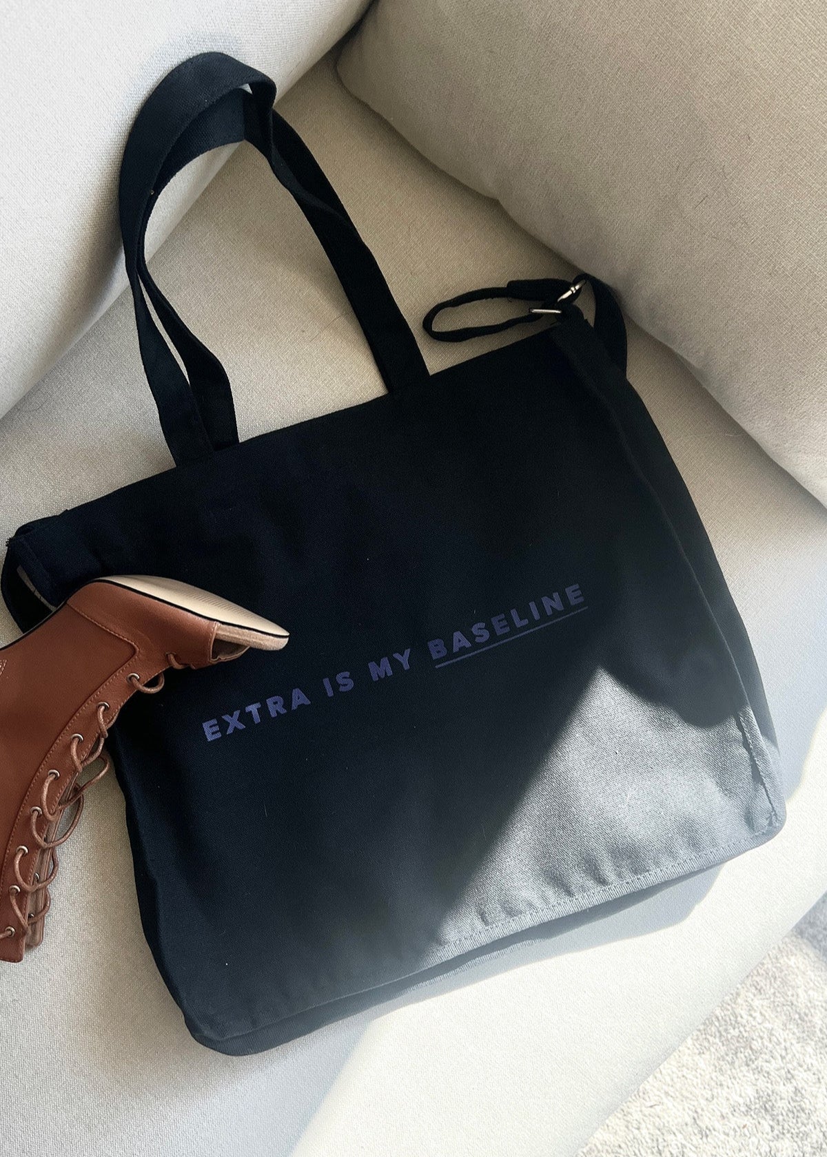Black bag with 'Extra is my baseline' text on a light-colored surface